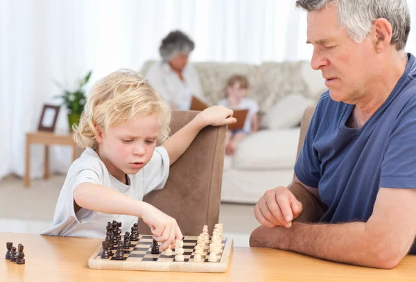 Ung pojke spelar schack med sin farfar — Stockfoto