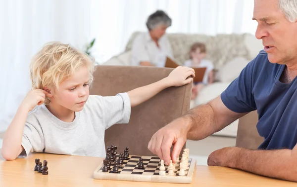 Ung pojke spelar schack med sin farfar — Stockfoto