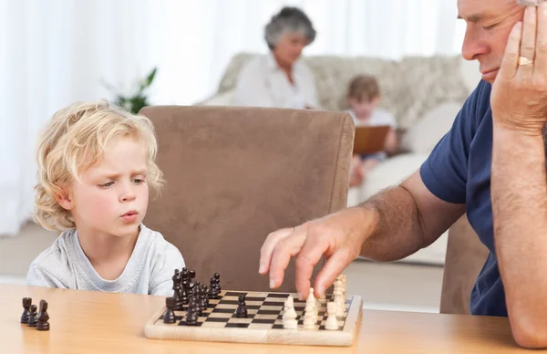 Young boy playing chess with his grandfather — Stock Photo, Image