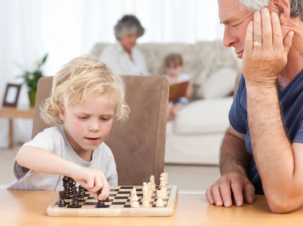Мальчик играет в шахматы со своим дедушкой — стоковое фото