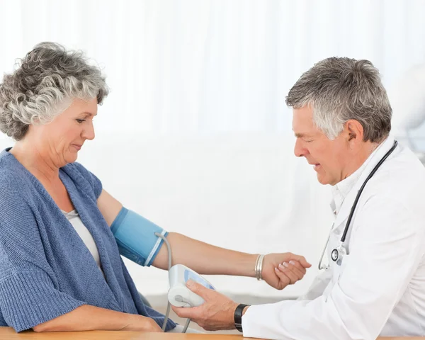 Senior läkare tar blodtrycket av hans patient — Stockfoto