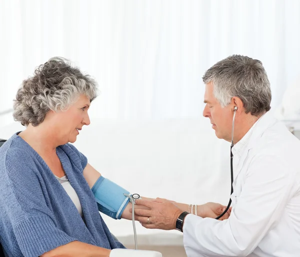 Starszy lekarz biorąc ciśnienia krwi pacjenta — Zdjęcie stockowe