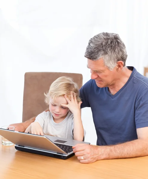 Lindo menino e seu avô olhando para seu laptop — Fotografia de Stock