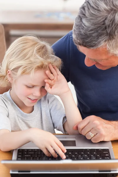 Chico encantador y su abuelo mirando su portátil — Foto de Stock