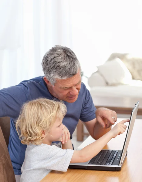Chico encantador y su abuelo mirando su portátil —  Fotos de Stock