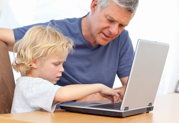 Chico encantador y su abuelo mirando su portátil — Foto de Stock