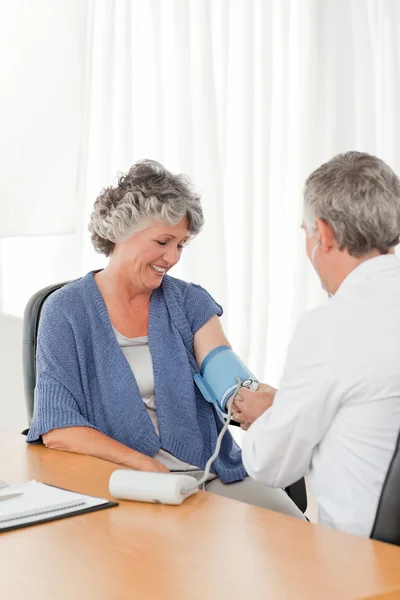 Een senior arts nemen de bloeddruk van zijn patiënt — Stockfoto