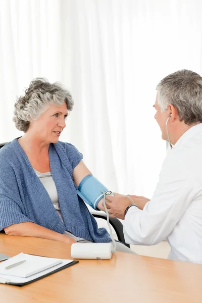 Starszy lekarz biorąc ciśnienia krwi pacjenta — Zdjęcie stockowe