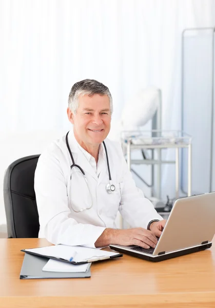 Vedoucí lékař pracující na svém notebooku ve své kanceláři — Stock fotografie