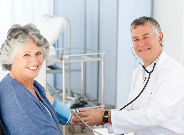 A senior doctor taking the blood pressure of his patient — Stock Photo, Image