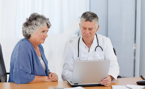 Vedoucí lékař se svým pacientem, při pohledu na laptop — Stock fotografie