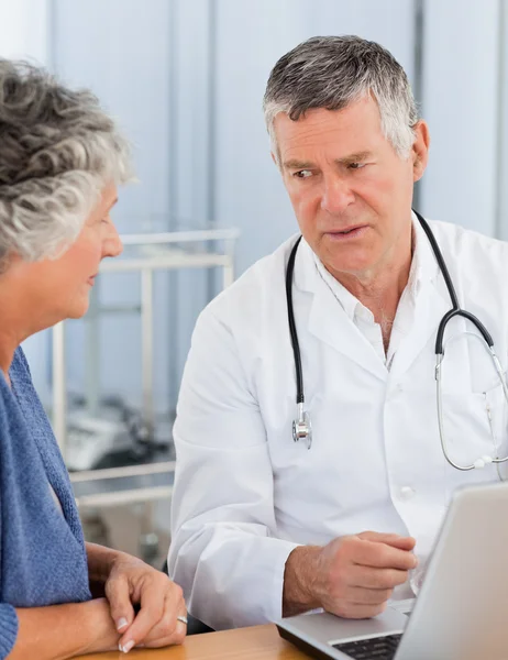 Un médico senior con su paciente mirando el portátil — Foto de Stock