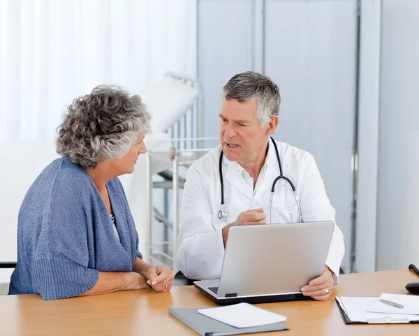 Un médico senior con su paciente mirando el portátil — Foto de Stock