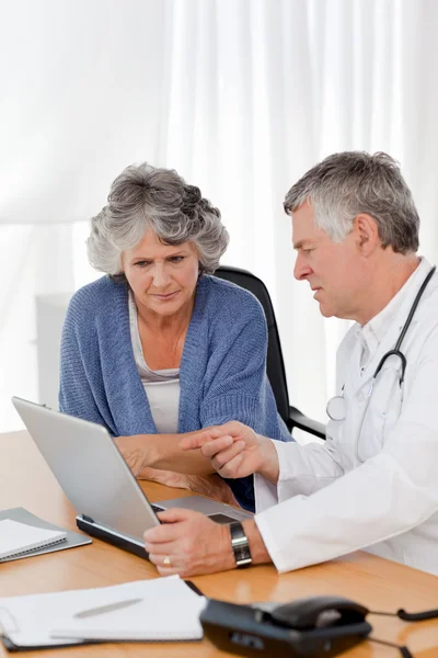 Een senior arts met zijn patiënt kijken naar de laptop — Stockfoto