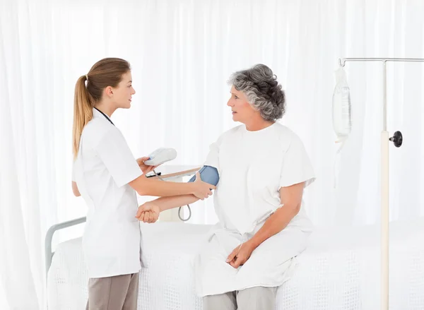 Nurse taking the blood pressure of her patient — Stock Photo, Image