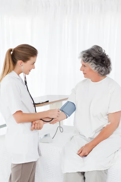 Pielęgniarka, biorąc jej pacjenta ciśnienia krwi — Zdjęcie stockowe
