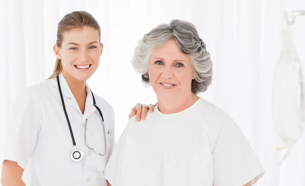 Senior med hennes sjuksköterskan tittar på kameran — Stockfoto