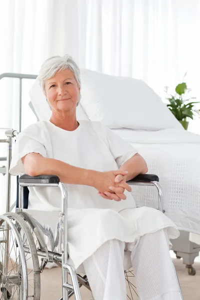 Äldre kvinna i hennes rullstol tittar på kameran — Stockfoto