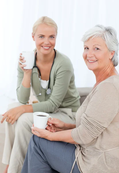 Doctor drinking with her patient — Stock Photo, Image