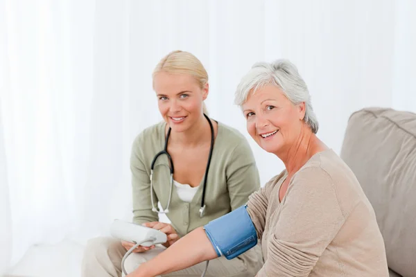 Lovely doctor taking the blood pressure of her patient — Stock Photo, Image
