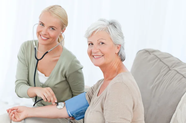 Lovely doctor taking the blood pressure of her patient — Stock Photo, Image