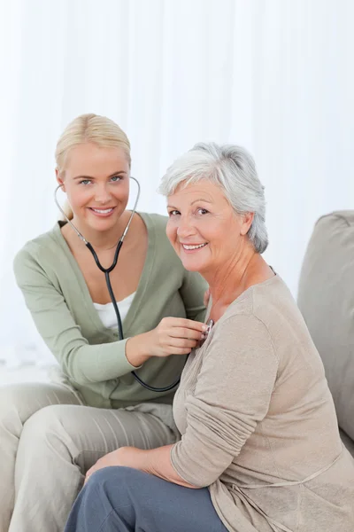 Nurse taking the heartbreat of her patient at home — Stock Photo, Image
