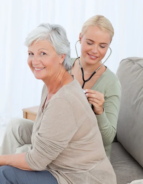 Nurse taking the heartbreat of her patient at home — Stock Photo, Image