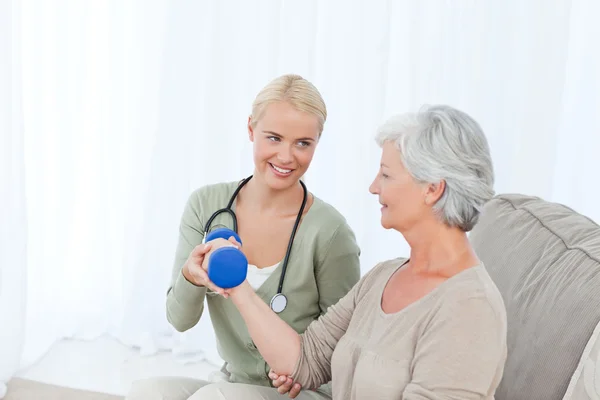 Beautiful nurse helping her patient to do exercises — Stock Photo, Image