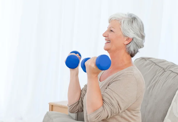 Senior doing her exercises on her sofa — Stock Photo, Image