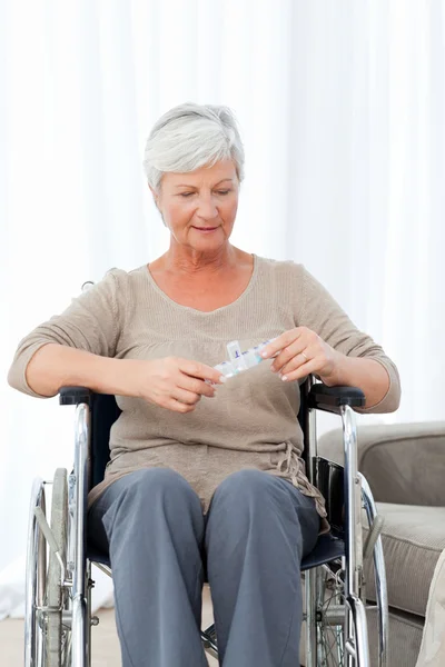 Старший в инвалидном кресле с таблетками — стоковое фото