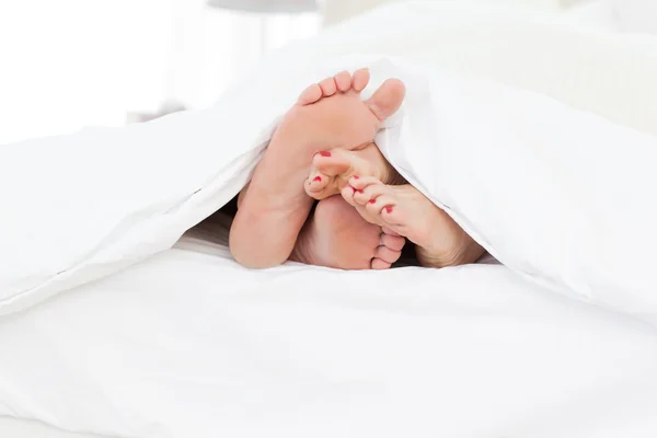 Koppel de voeten in het bed — Stockfoto
