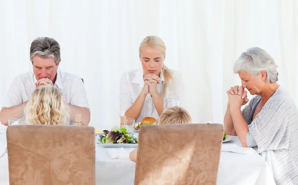 Красивая семья молится за столом — стоковое фото