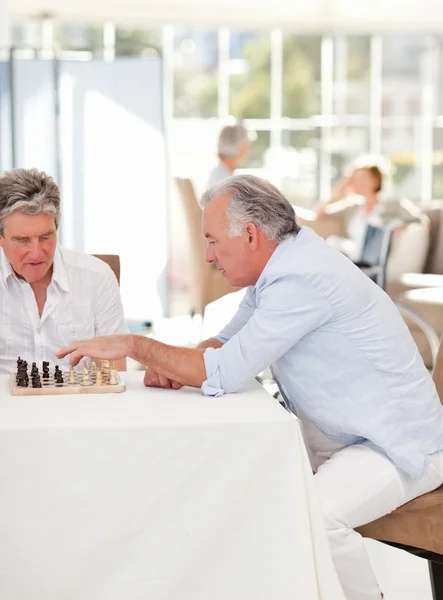 Seniorzy, gra w szachy w salonie — Zdjęcie stockowe