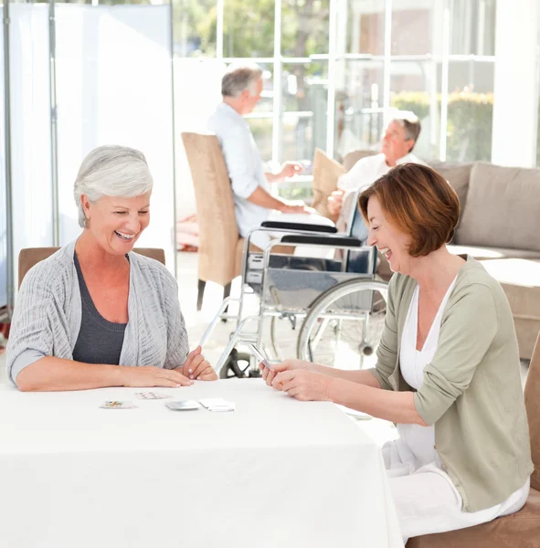 Mulheres seniores jogando cartas enquanto seus maridos estão falando — Fotografia de Stock