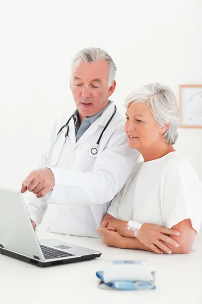 医師と彼の患者をノート パソコンを見て — ストック写真