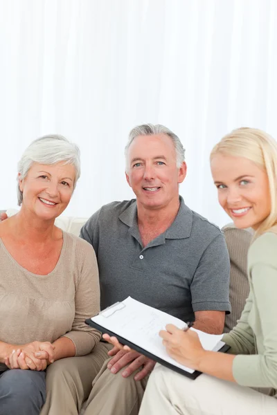 Seniors with doctor looking at the camera at home — Stock Photo, Image