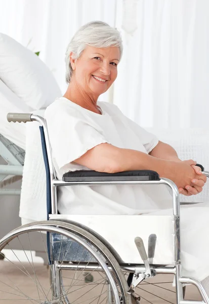 Senior vrouw in haar rolstoel kijken naar de camera — Stockfoto