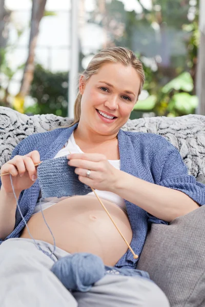 妊娠中の女性は彼女のソファーで編み物 — ストック写真