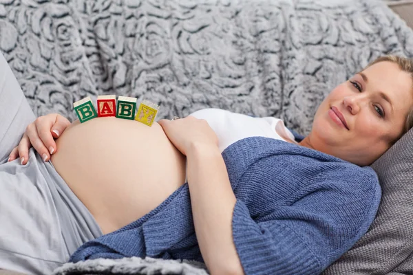 Jeune femme enceinte avec des cubes sur le ventre — Photo