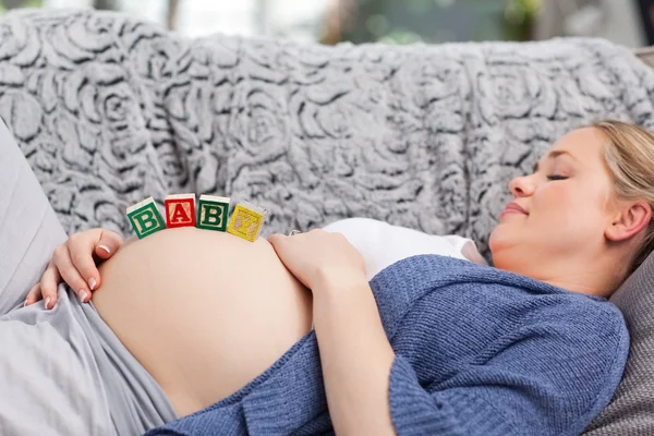 Mujer joven embarazada con cubos en el vientre — Foto de Stock