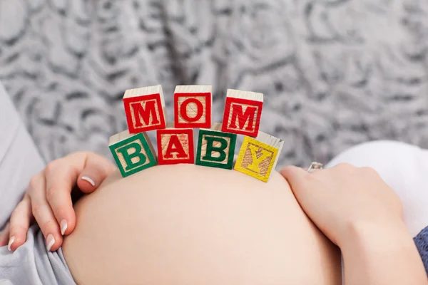 Mujer joven embarazada con cubos en el vientre — Foto de Stock
