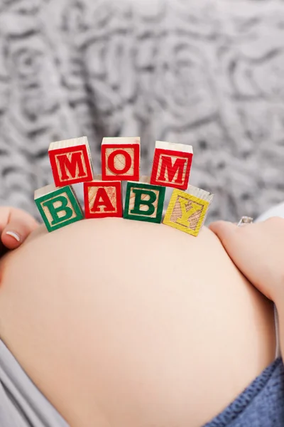 Schwangere junge Frau mit Würfeln auf dem Bauch — Stockfoto