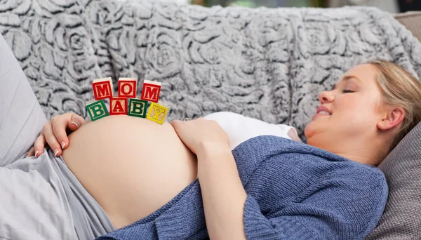 Zwangere jonge vrouw met kubussen op haar buik — Stockfoto