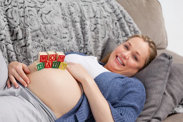 Schwangere junge Frau mit Würfeln auf dem Bauch — Stockfoto
