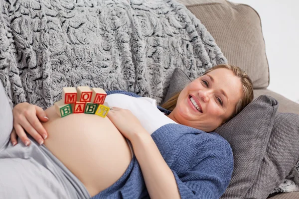 Giovane donna incinta con cubi sulla pancia — Foto Stock