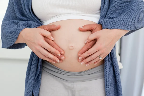 임신한 여자의 뱃속에 한 쌍의 손 — 스톡 사진