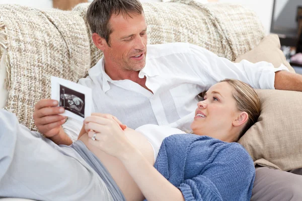 Couple looking at an X-ray on their couch at home — Stock Photo, Image
