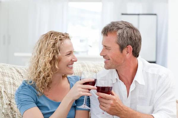 Casal bebendo vinho tinto na sala de estar — Fotografia de Stock