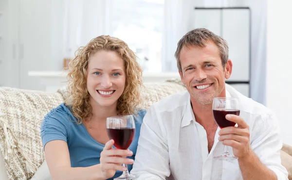 Pár pít červené víno v obývacím pokoji — Stock fotografie