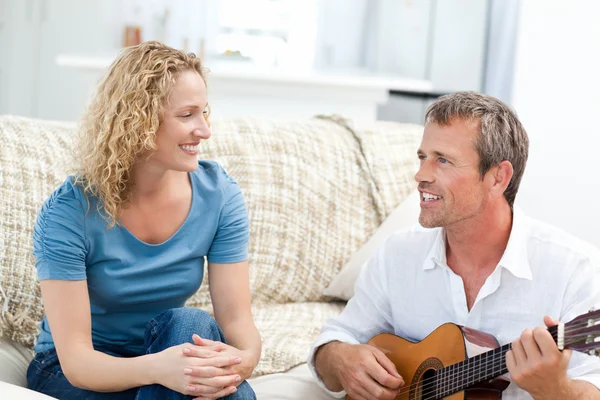 自宅で妻が彼女のギターを弾く男のロマン. — ストック写真